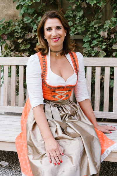 Alexandra Lendeckel - im Dirndl sitzend auf der Bank